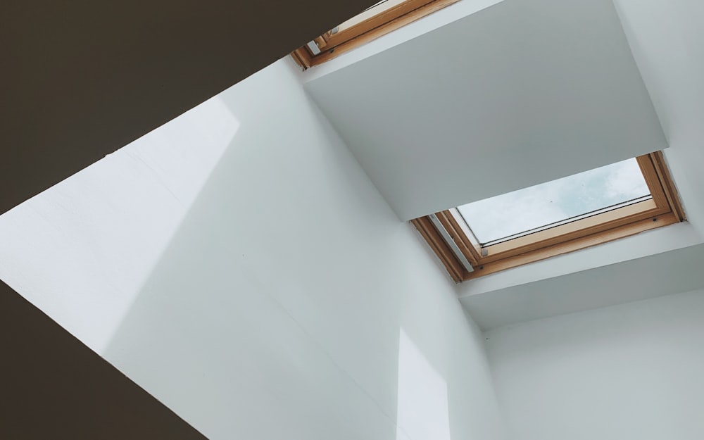 A wood-framed residential skylight in a bright sloped ceiling.